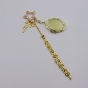 Detail view of golden mesh bag charm with star carabiner and long metal tassel chain