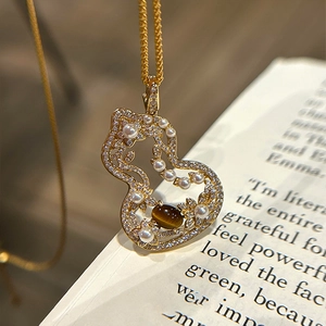 Macro shot of gold necklace with tiger eye stone and pearl gourd pendant on a vintage book