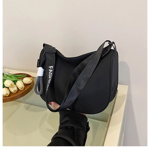 Detail of black half-moon shoulder bag with FASHION letter strap and rope decoration