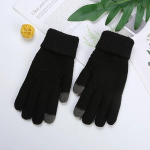 Detailed view of black knitted touchscreen gloves with grey fingertips on a white table
