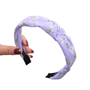 Purple knotted headband with white daisy pattern and protective black tips on white backdrop