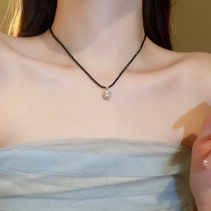Gros plan d'un pendentif en cristal carré scintillant sur un collier de perles noires