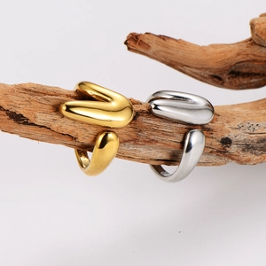 Minimalist V-shaped stainless steel rings in gold and silver finish on wooden branch