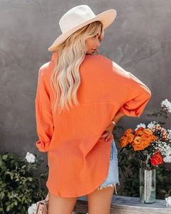 Detail view of orange cotton linen shirt texture and breathable casual sleeve design