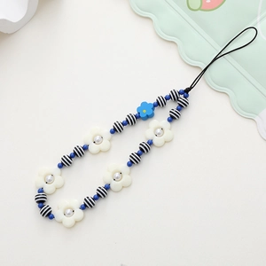 Detail of handcrafted beaded phone charm with white flowers and blue frosted beads