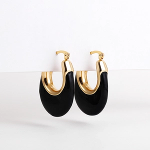 Detail shot of U-shaped gold and black enamel hoop earrings with polished metal texture