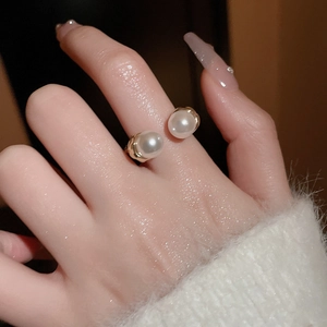 Detailed close-up of an elegant double pearl open ring featuring a golden metal band