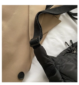 Detail of adjustable shoulder strap and black quilted texture on a fashion crossbody bag