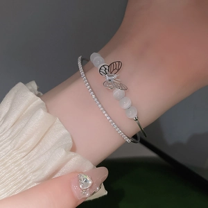 Nahaufnahme von silbernen Armbändern mit Opalperlen und Schmetterlingsanhänger