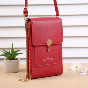 Detail of red faux leather cell phone bag with dual gold zippers and flower charm