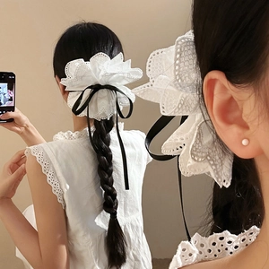 Chouchou élégant en dentelle blanche avec nœud noir porté sur une tresse