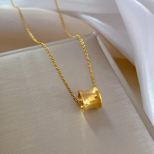 Detail of gold small waist pendant necklace on elegant beige surface with white silk fabric