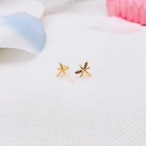 Macro view of gold-plated dragonfly stud earrings with detailed black spots