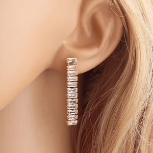 Sparkling gold zircon drop earrings with rectangular clear crystals worn by a model