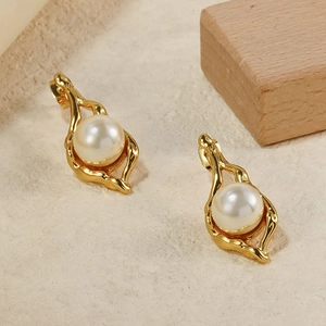 Boucles d'oreilles géométriques dorées avec grandes perles blanches sur fond pierre