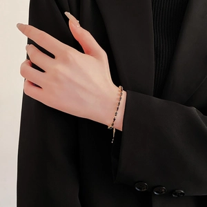 Close-up of minimalist gold bracelet featuring black gemstones on a model wrist