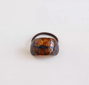 Detailed macro view of the amber tortoiseshell acetate texture on a round hair tie