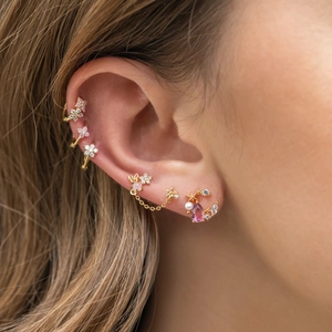 Dettaglio di orecchini stella e luna in oro 18K con cristalli rosa sull'orecchio