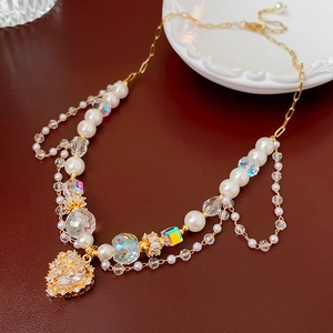 Detail of layered pearl and crystal necklace with a gold-bordered heart pendant charm
