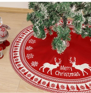 Close-up of a red knitted Christmas tree skirt with reindeer, snowflakes and Merry Christmas text