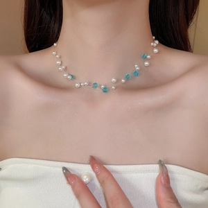 Detail shot of a double-layer pearl and blue crystal beaded necklace on a model