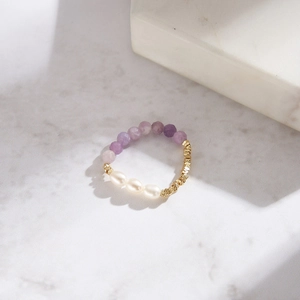 Detail of beaded bracelet with faceted purple beads, white pearls and gold accents