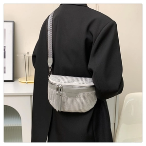 Fashionable silver rivet crossbody bag with wavy shoulder strap on model's shoulder