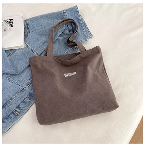 Detail of brown corduroy tote bag with Fashion label and stylish everyday accessories