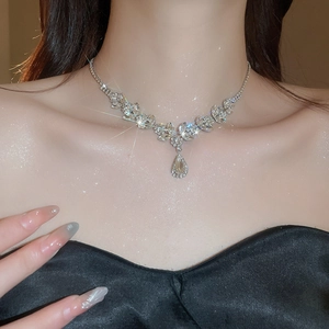 Macro shot of sparkling wheat leaf necklace with pear-cut crystal pendant on model neck
