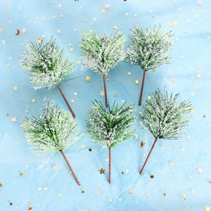 Detail of six green artificial pine needles with white frost tips on star pattern cloth