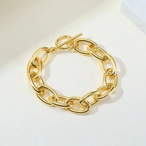 Detail of chunky gold stainless steel chain bracelet with a modern OT toggle clasp closure