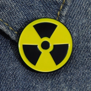 Macro shot of yellow radioactive biohazard enamel pin on blue denim fabric texture