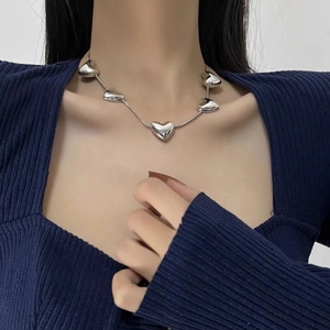 Polished silver heart pendant necklace on a sleek snake chain worn by a female model