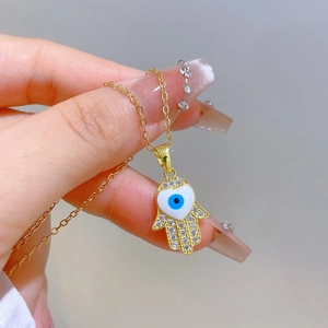 Elegant gold hamsa hand necklace with blue evil eye pendant and zircon stones