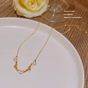 Detail of gold heart necklace with white shell inlay pendants on white ceramic plate