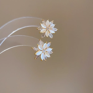 Macro detail of elegant gold flower stud earrings with opal petals and zircon accents