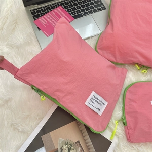 Pink waterproof travel organizer set with contrast neon zippers on white plush carpet