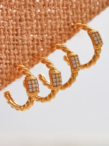 Macro detail of 18k gold plated twisted hoop earrings with micro paved cubic zirconia