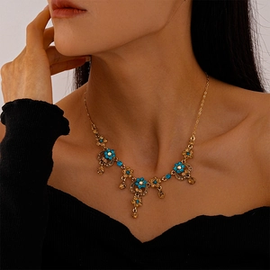 Detailed close-up of vintage flower heart necklace with blue and amber crystals