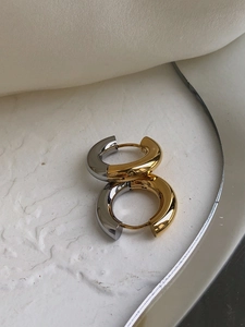 Macro view of two-tone gold and silver spliced titanium steel hoop earrings on stone