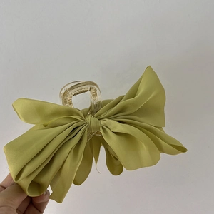 Detail of a large grass green satin bow hair claw clip made of premium silk fabric