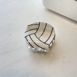 Detail shot of a round hair claw clip with a realistic black and white volleyball pattern