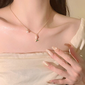 Elegant gold chain necklace featuring a pink tulip pendant and white pearl on a model