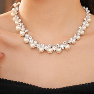 Close-up of pearl and geometric crystal necklace showing detailed silver setting and texture