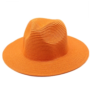 Dettaglio della trama intrecciata arancione e dell'ala larga di questo cappello di paglia
