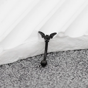 Macro view of a black stainless steel eyebrow ring featuring a gothic bat design