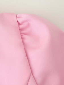 Détail de la texture du tissu rose à manches bouffantes et design plissé smocké