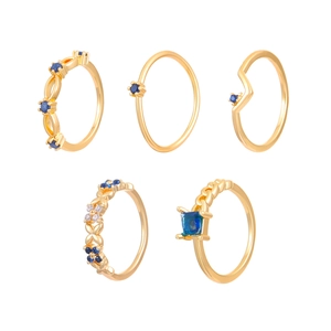 Vintage 5-piece gold ring set with blue crystals and hollow patterns on white background