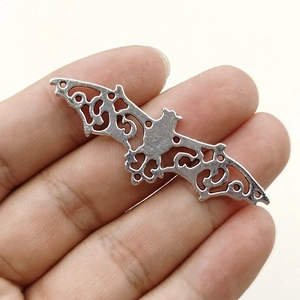 Detail of silver alloy bat pendant with intricate hollow design for DIY jewelry making