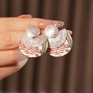 Detail of round wood earrings featuring desert cactus prints and textured silver metal tops